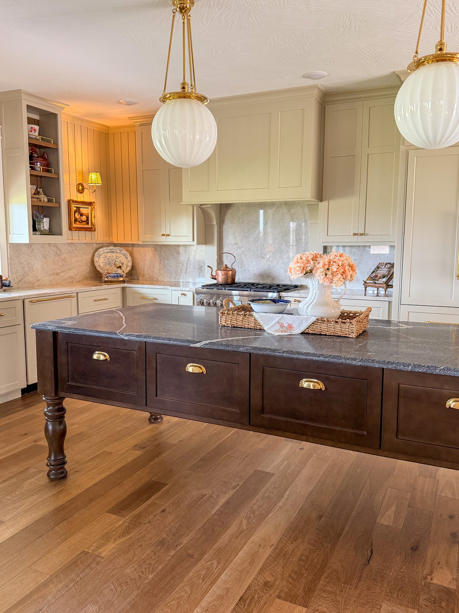 Modern kitchen with a large island, wooden flooring, and pendant lights.